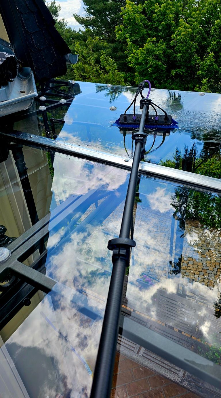 Professionelle Fensterreinigung mit OVA8-Teleskopstange, spiegelt sich im Glas