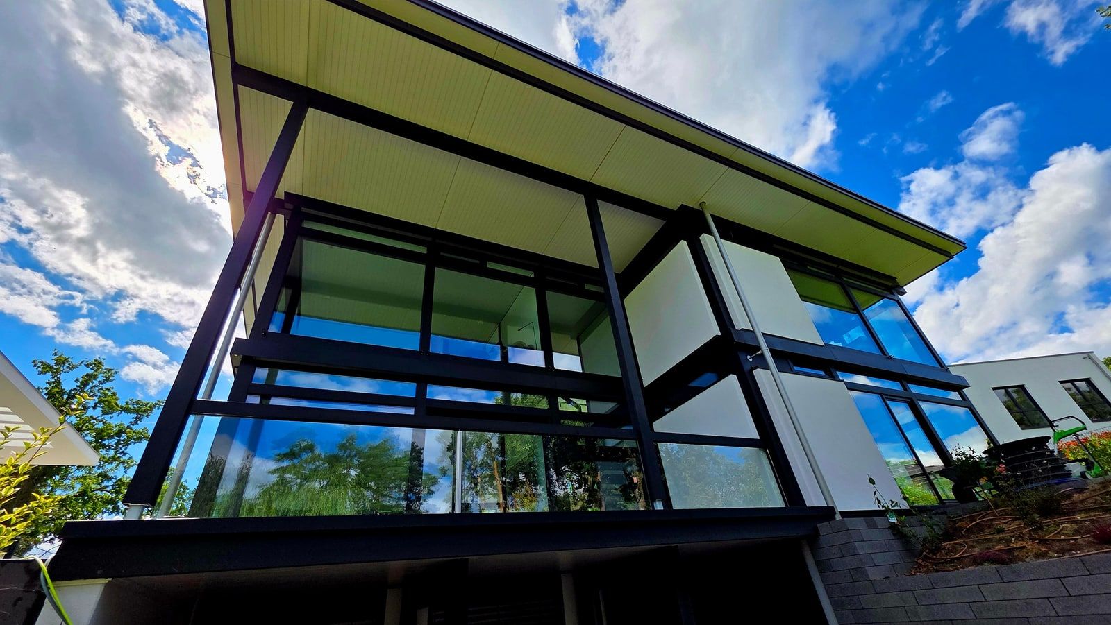 Glashaus mit dunkler Pfosten-Riegel-Konstruktion von unten fotografiert