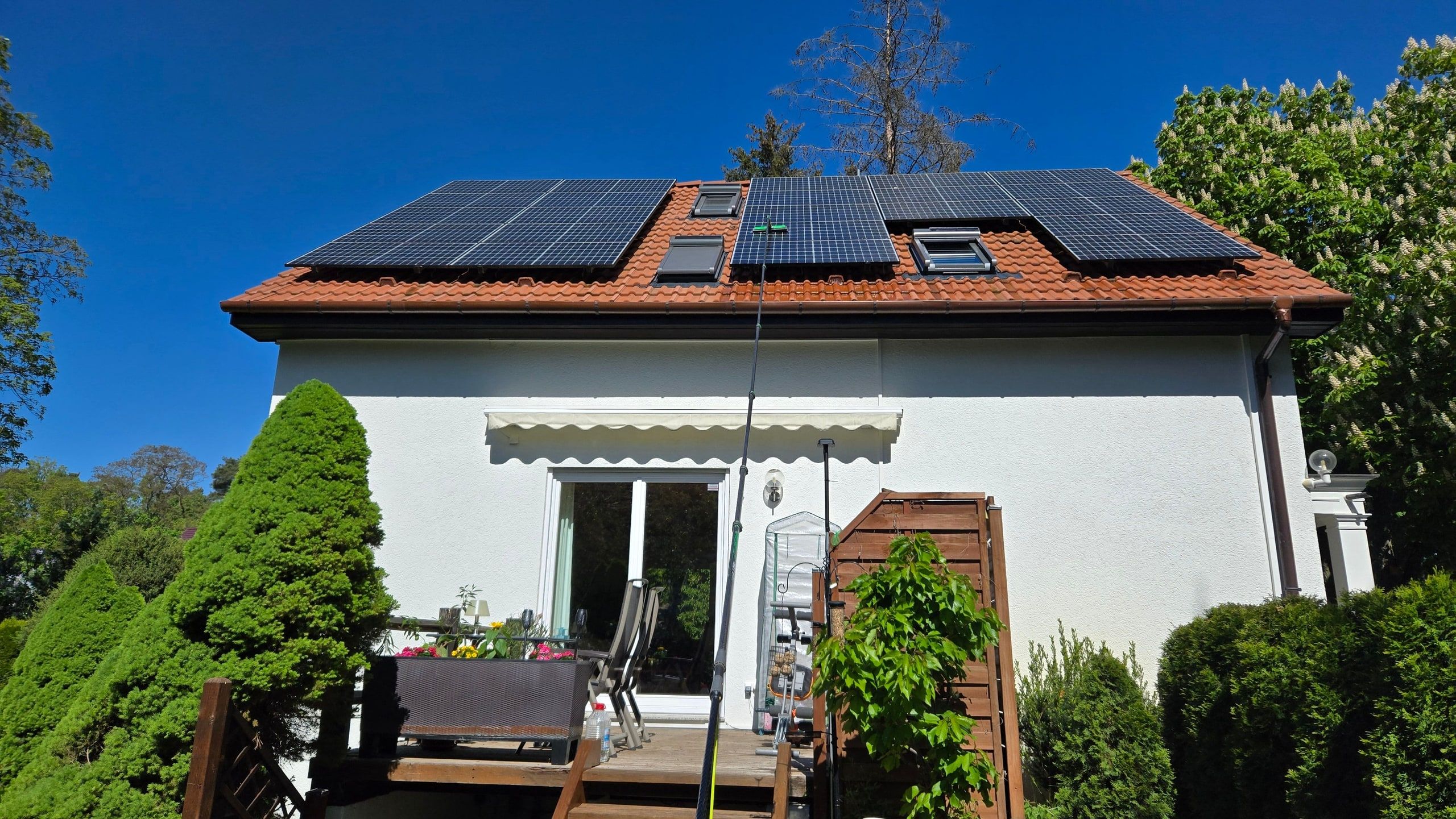 Reinwasserstange reicht bis zu den Solarmodulen auf dem Dach eines Wohnhauses