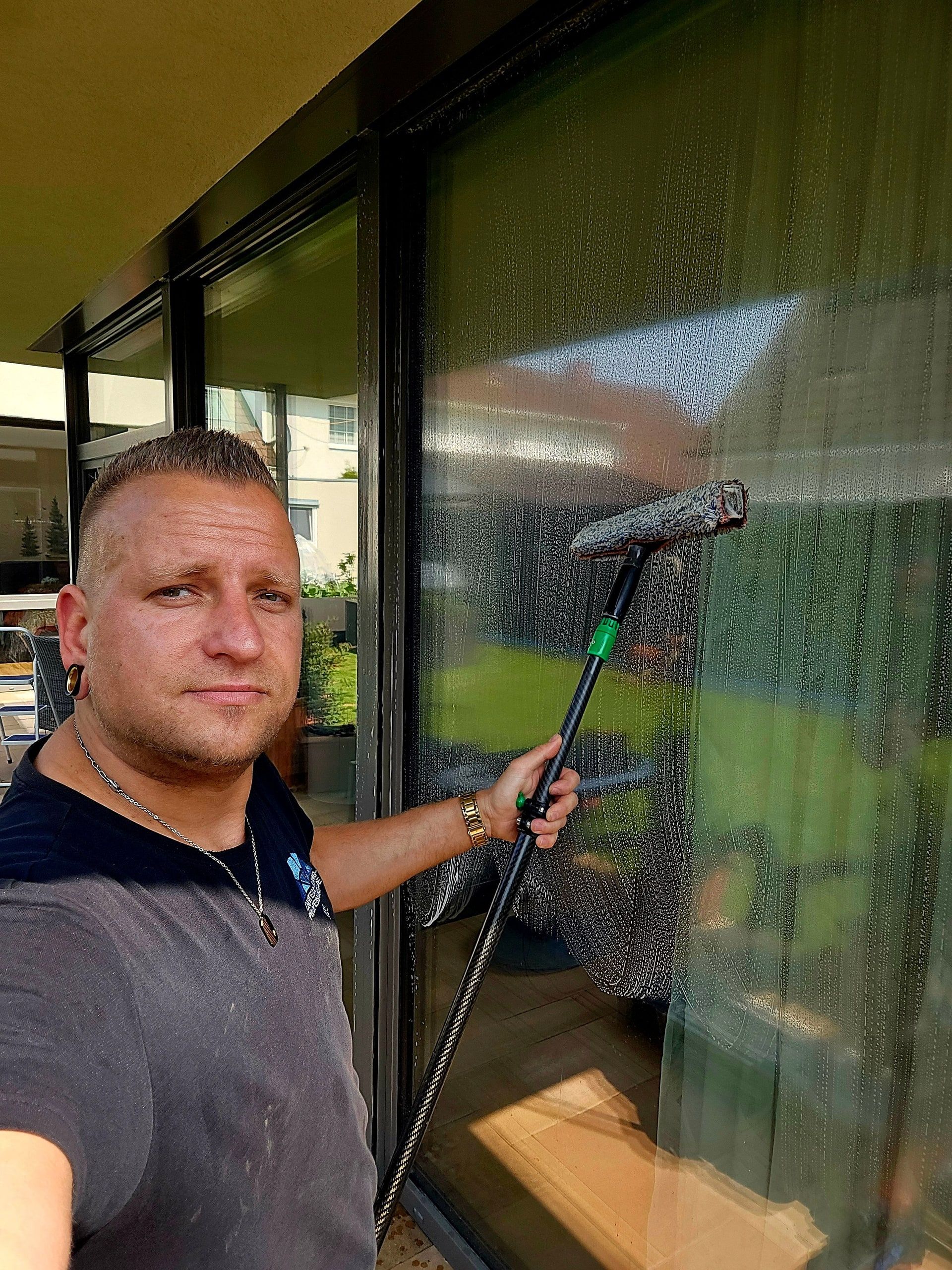 Benjamin O. Giese reinigt mit dem Abzieher eine große Glasfront