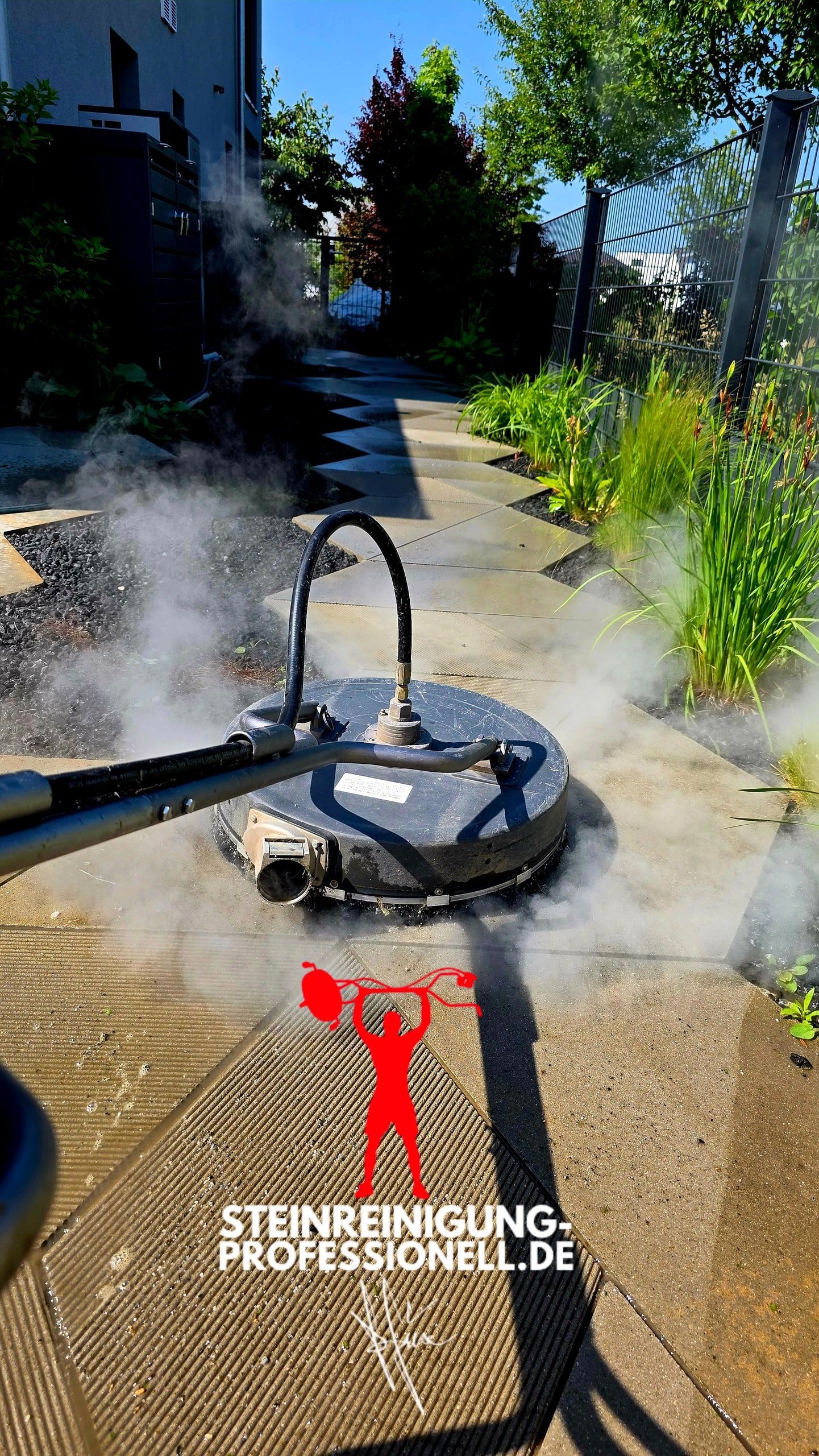 Flächenreiniger arbeitet mit heißem Wasser auf einem Plattenweg, sichtbarer Wasserdampf