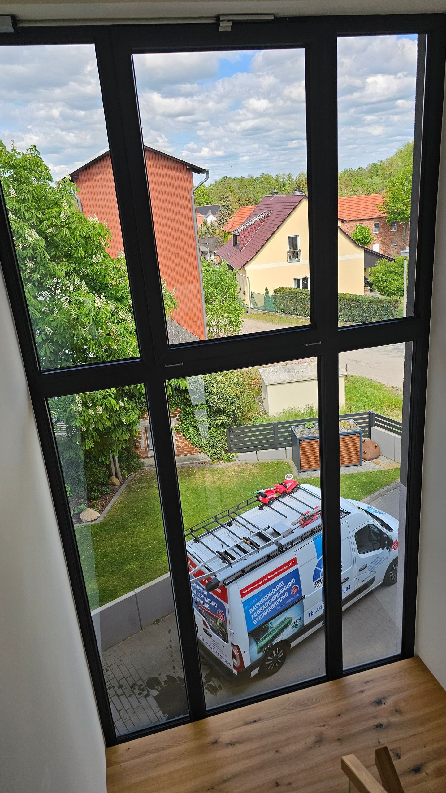 Blick durch ein großes, frisch gereinigtes Fenster auf das Wohnumfeld