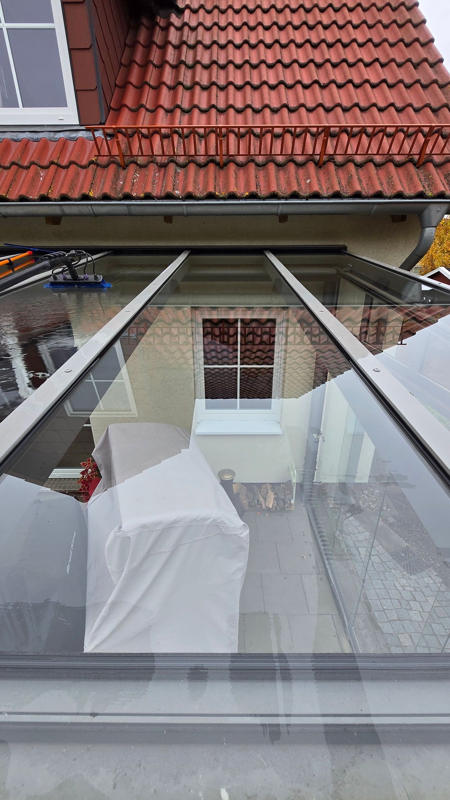 Saubere Glasdachfläche eines Wintergartens mit Spiegelung des Wohnhauses in Berlin