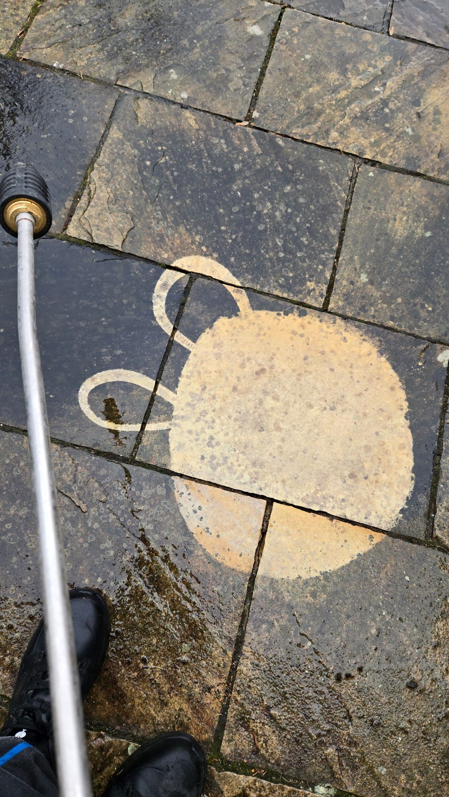 Freigereinigter Kreis auf dunklem Natursteinpflaster als Reinigungsprobe