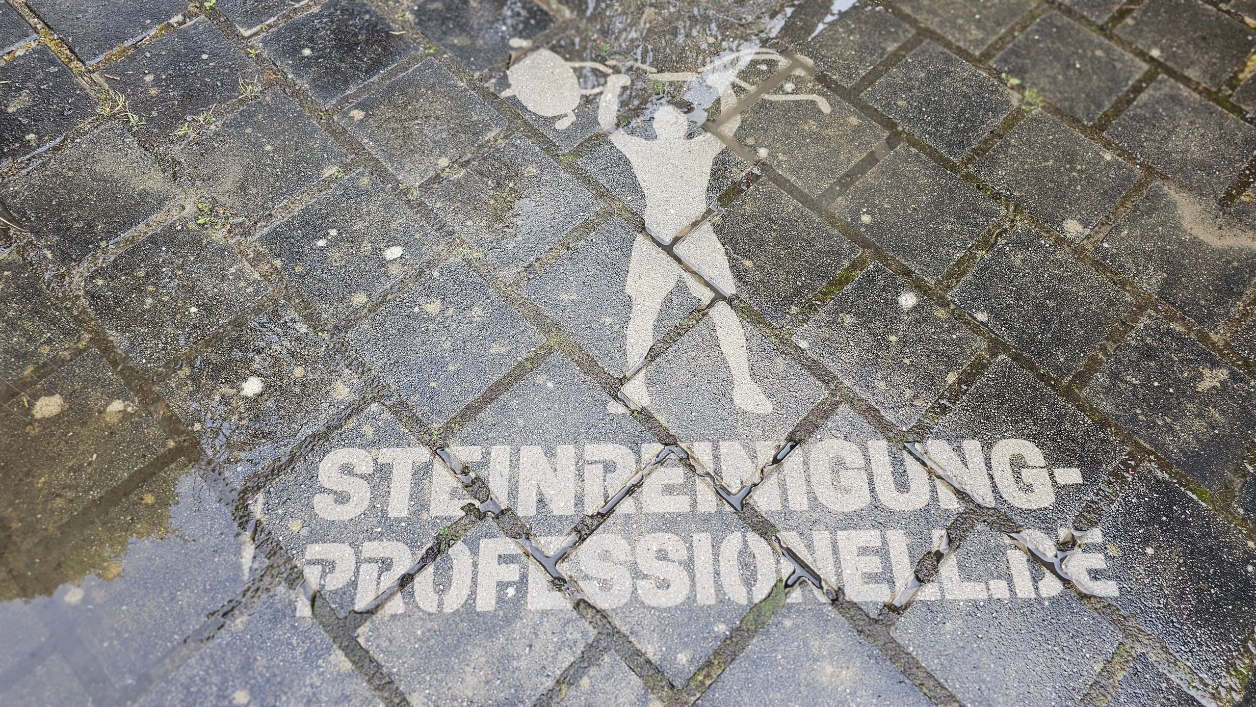 Freigereinigtes Firmenlogo im Pflaster als Beweis der Reinigungswirkung