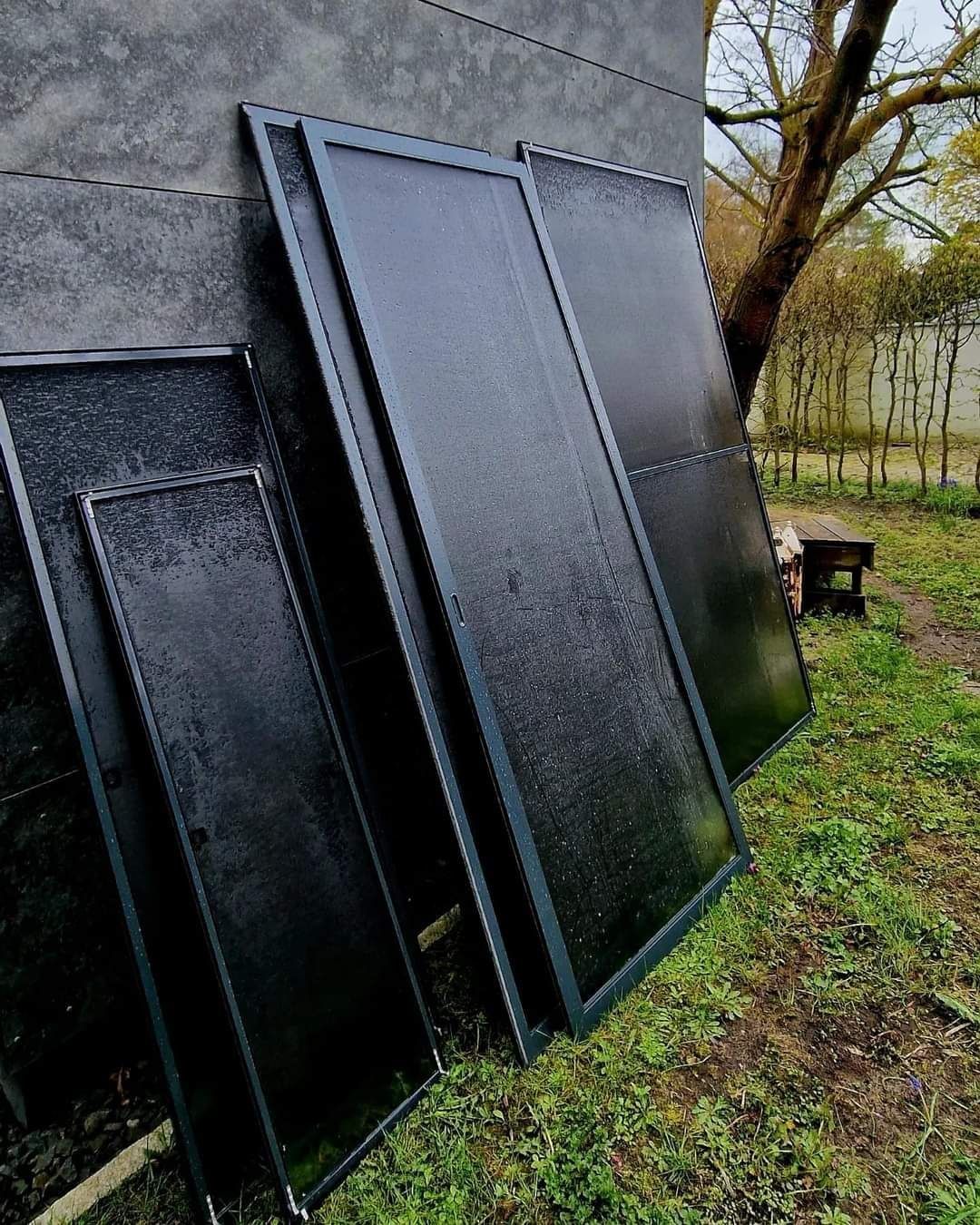 Mehrere gereinigte Solarmodule lehnen zum Trocknen an einer Hauswand