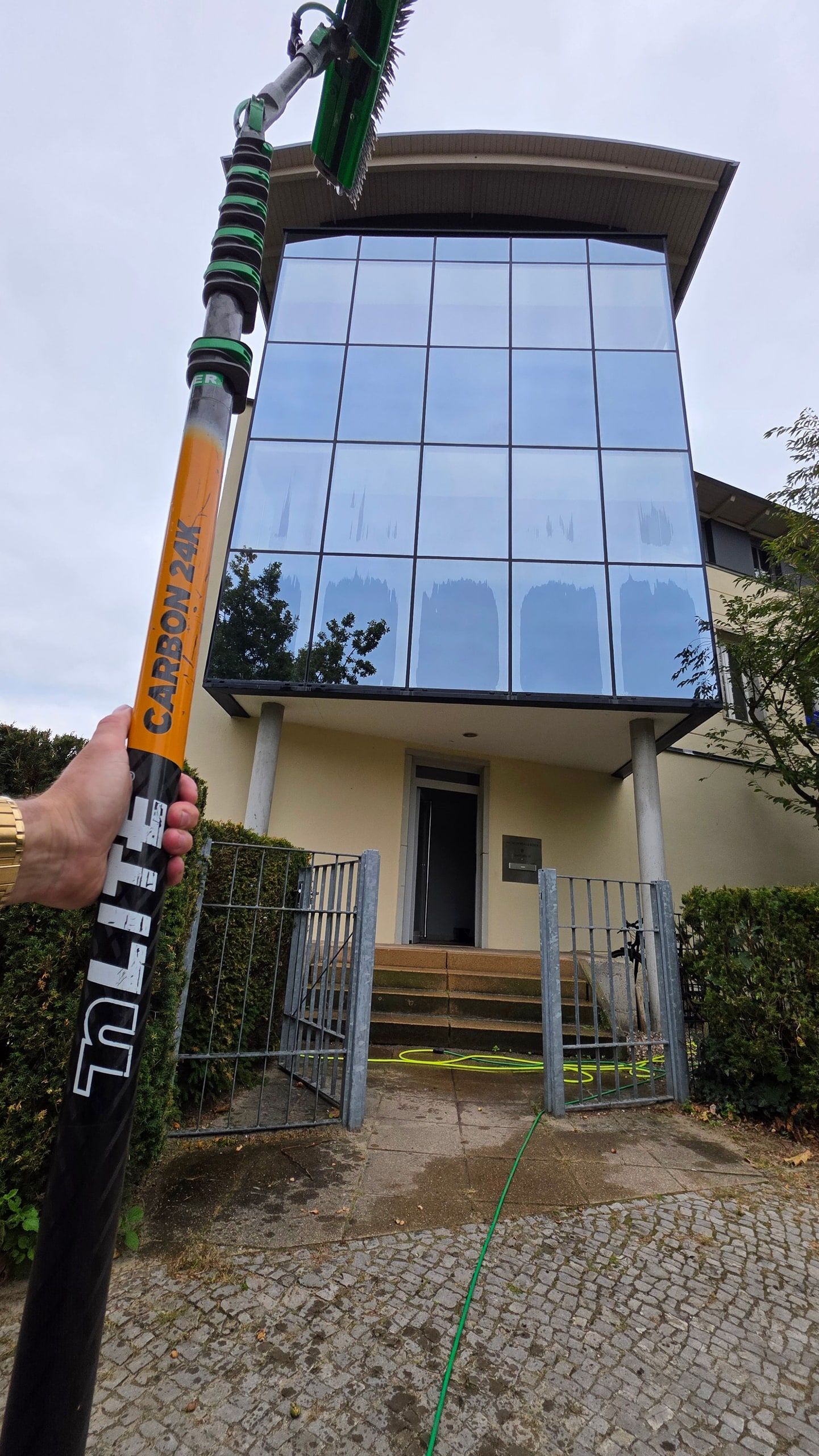 Carbon-Teleskopstange vor der gläsernen Fassade eines mehrgeschossigen Gebäudes