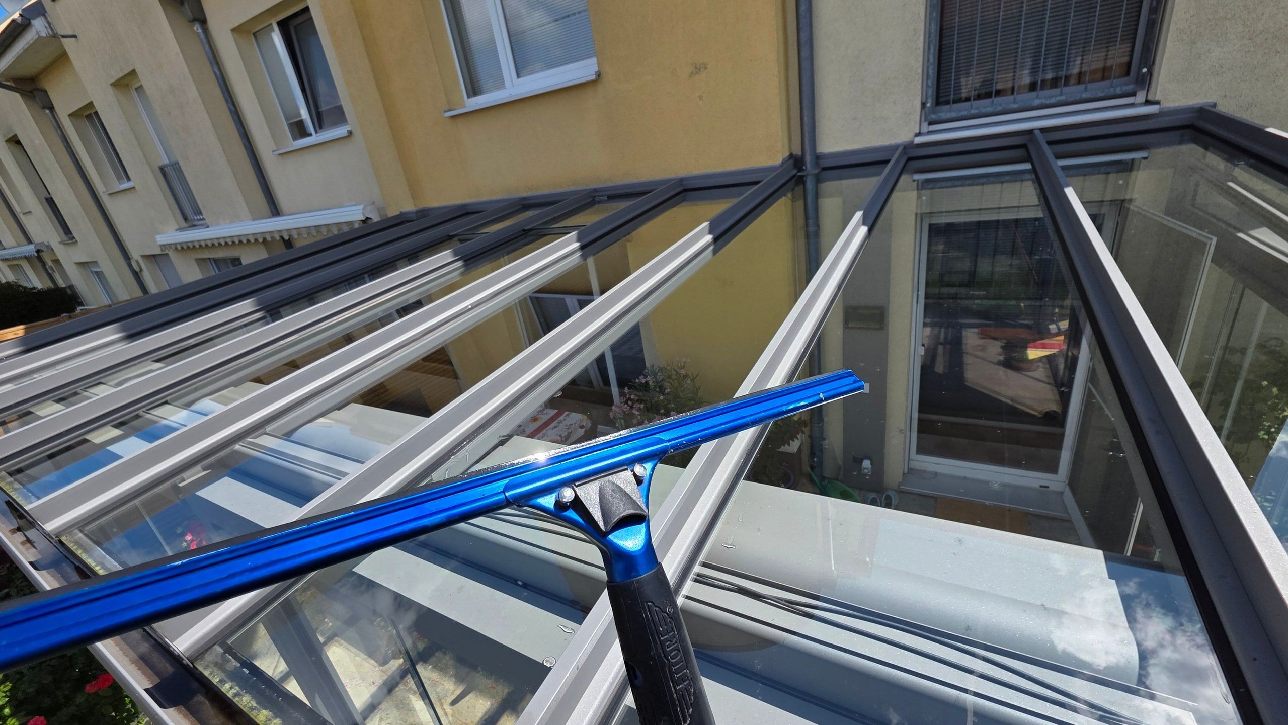 Moderner anthrazitfarbener Glasanbau mit gereinigten Glasflächen an einem Wohnhaus