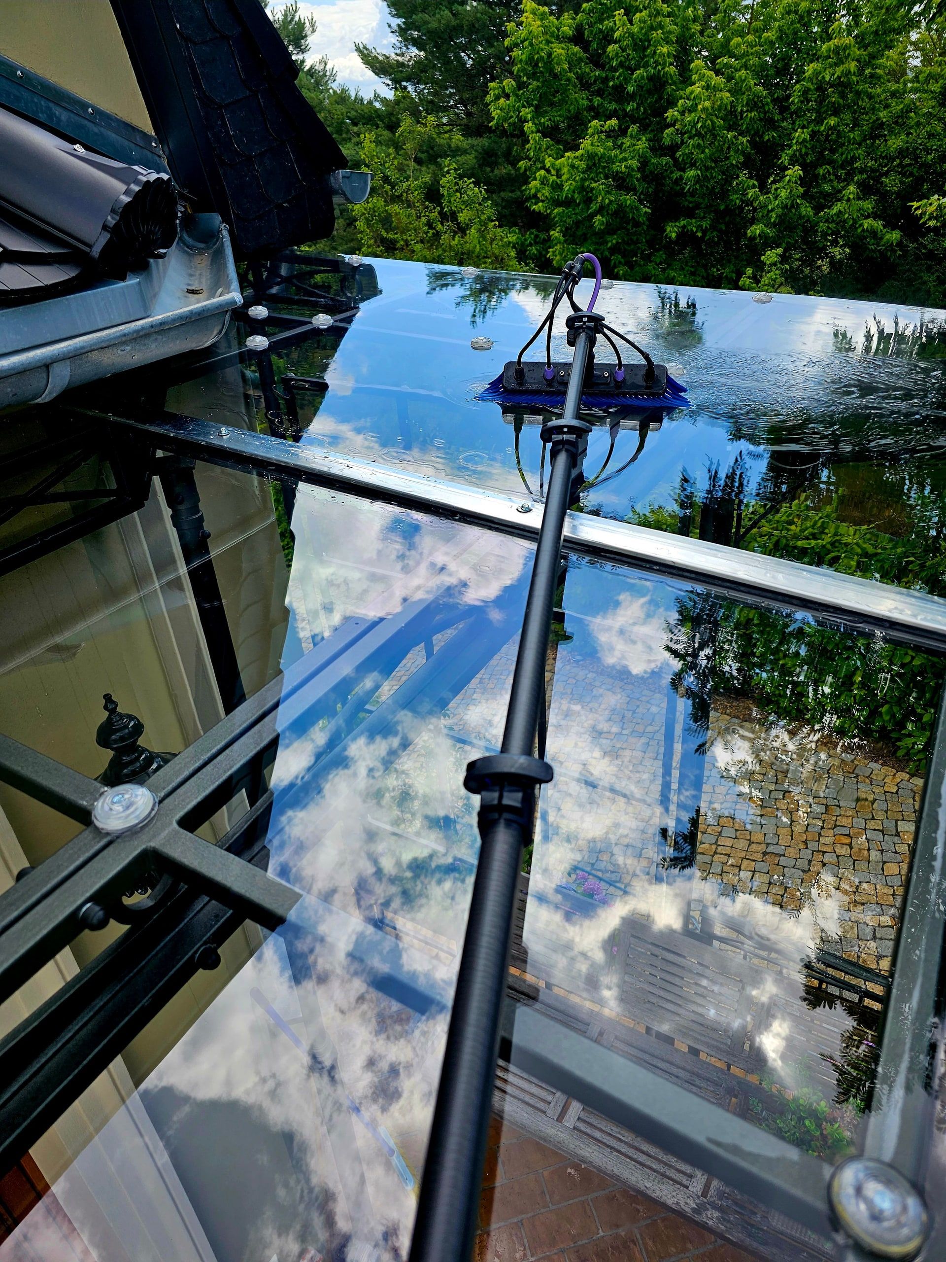 Nasses Glasdach einer Terrassenüberdachung während der Reinigung