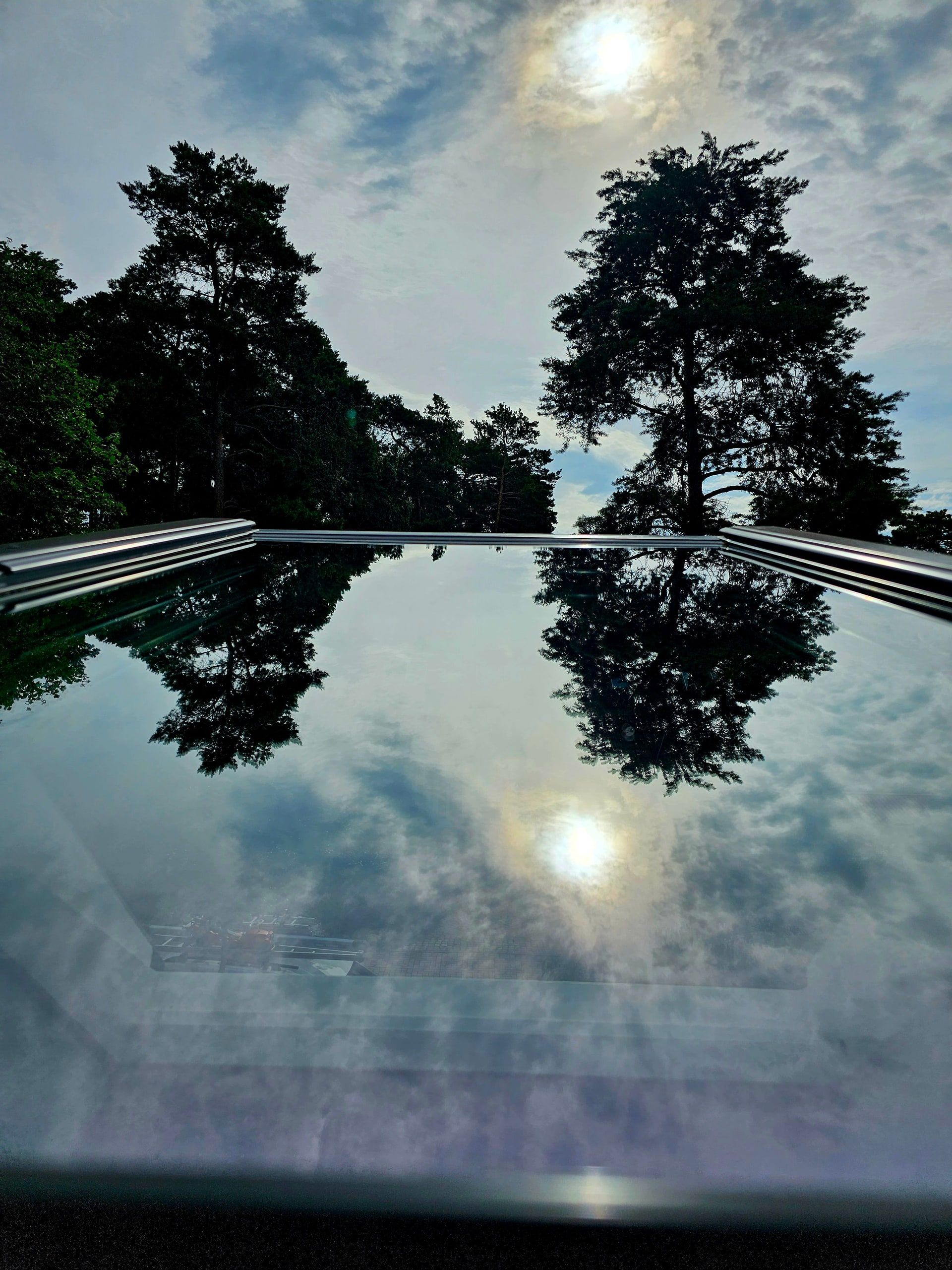 Sonne und Bäume spiegeln sich in der frisch gereinigten Glasdachfläche
