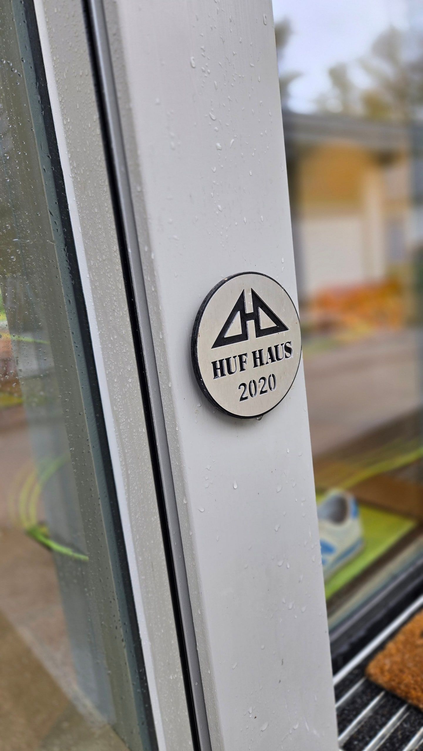 HUF-HAUS-Plakette mit Baujahr am Rahmen einer frisch gereinigten Glasfront
