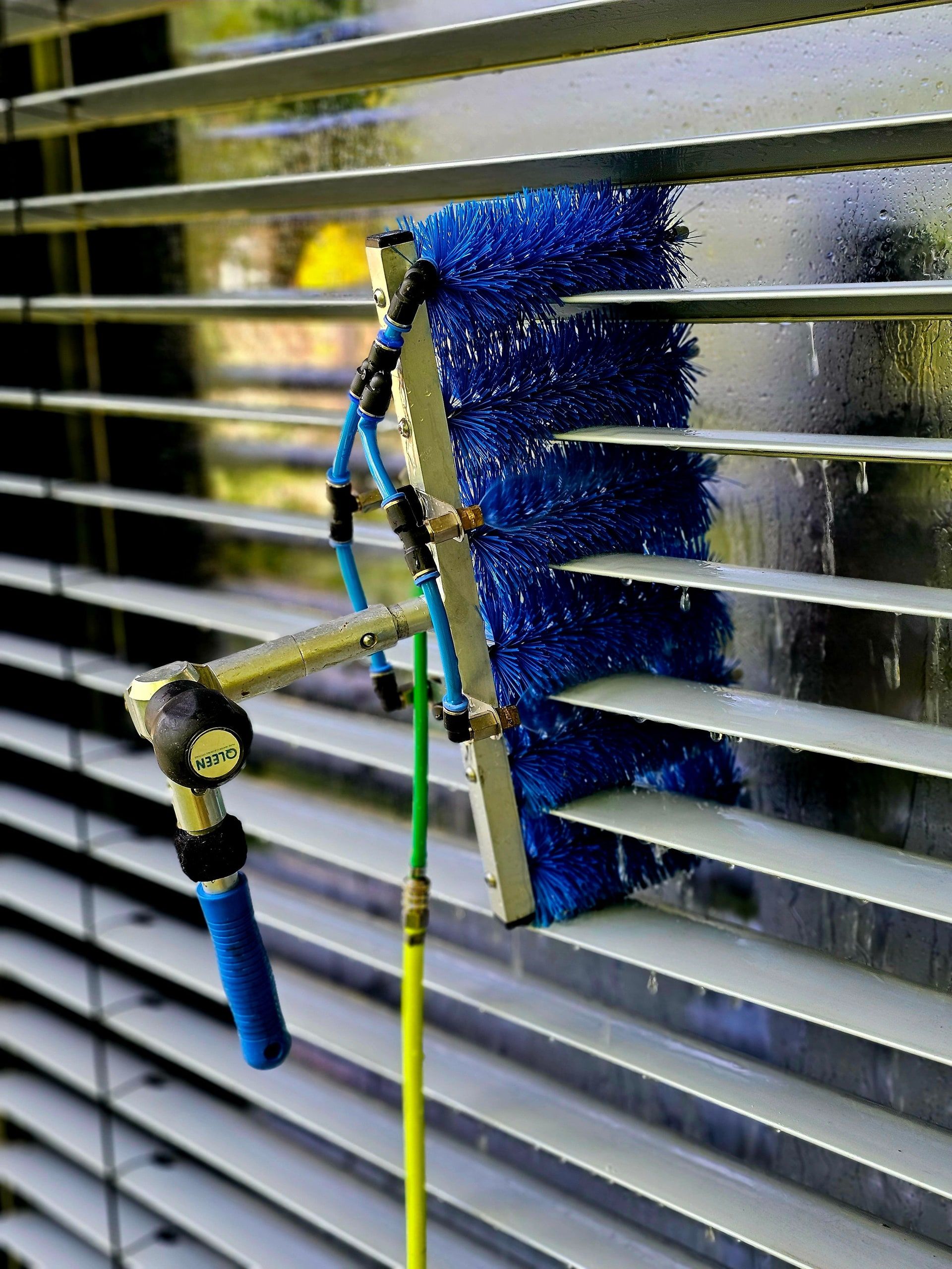 Blaue Bürste reinigt die Lamellen einer Außenjalousie