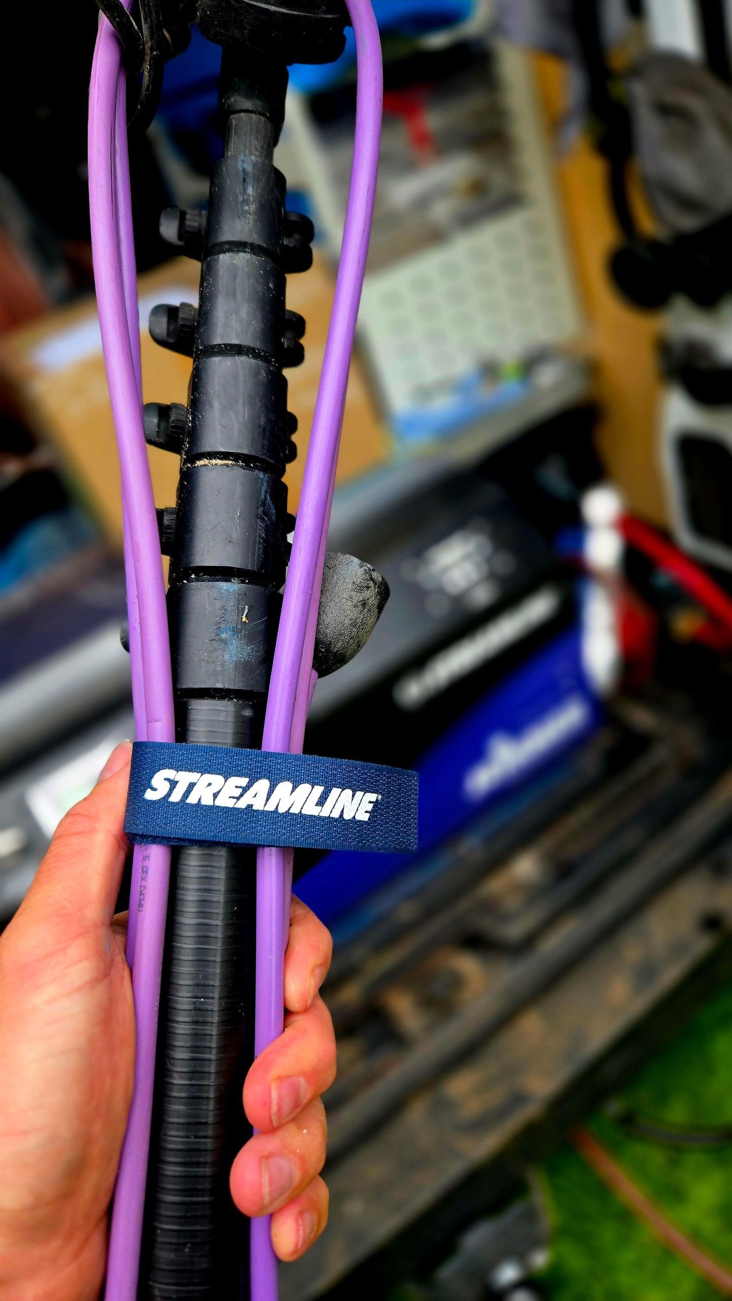 Carbonstange mit geführtem Wasserschlauch, von einem Klettband zusammengehalten, in der Hand vor dem Einsatzfahrzeug