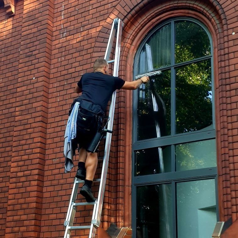 Fensterreinigung von der Leiter an einem Bogenfenster in den Anfangsjahren