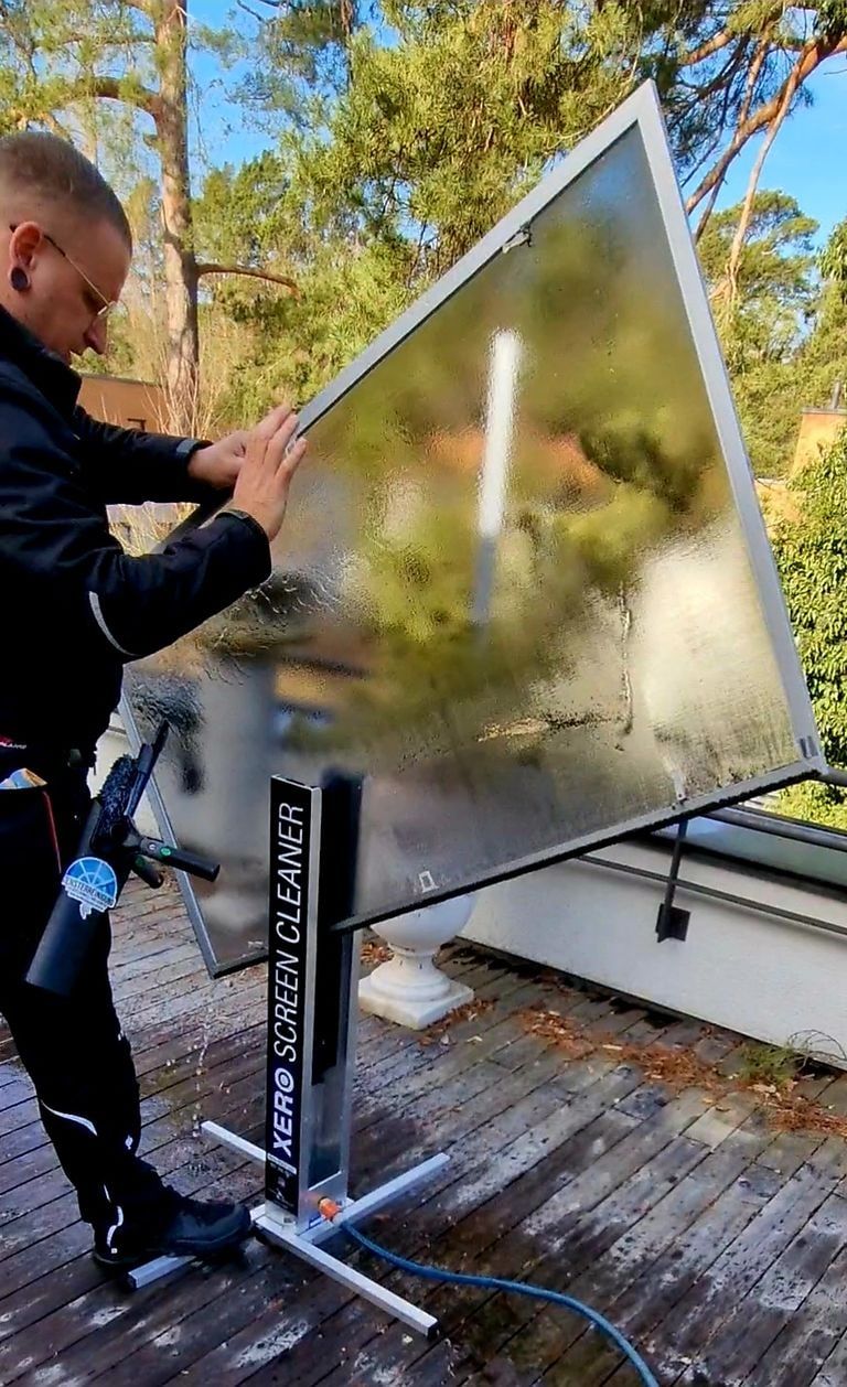 Benjamin O. Giese reinigt ein Fliegengitter am Arbeitsständer