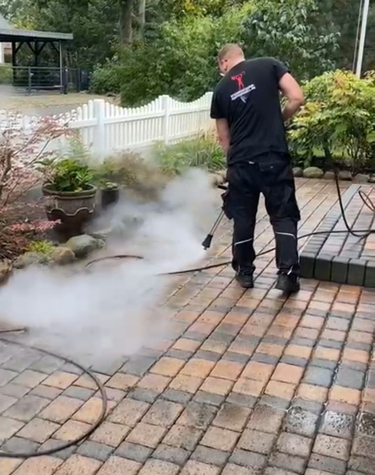 Heißwasser-Steinreinigung einer Pflasterfläche mit sichtbarem Dampf