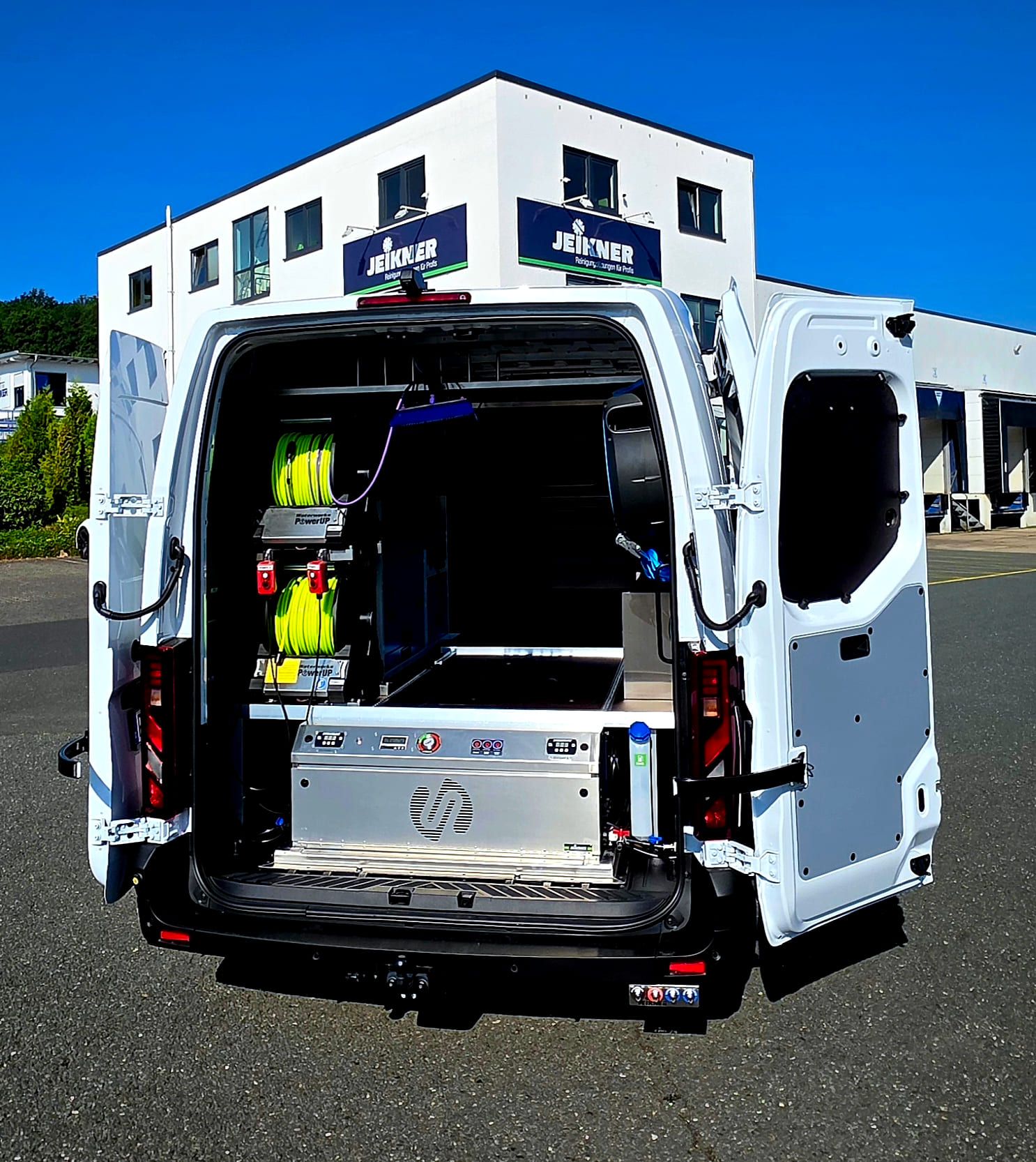 Der fertig ausgebaute Elektro-Transporter mit offenen Hecktüren vor dem Jeikner-Gebäude: Schlauchwinden links, Smartank im Stahlrahmen unten